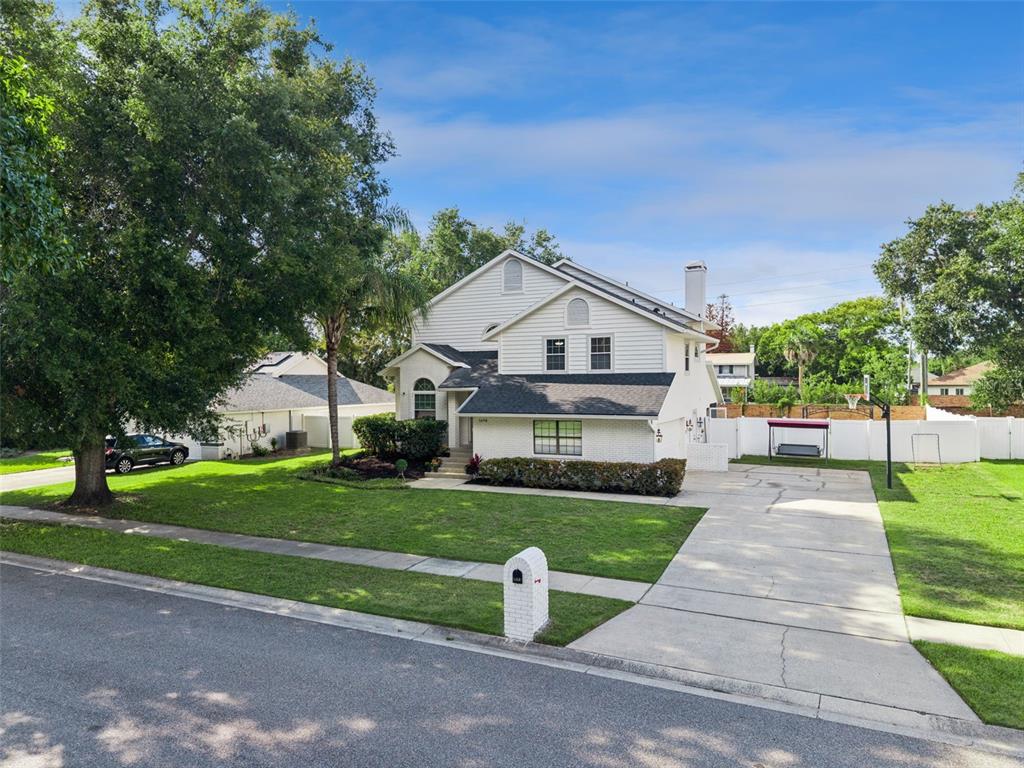 A two-story white house with a brick facade, a driveway, and a large front lawn — 1458 ROYAL CIRCLE, APOPKA, FL