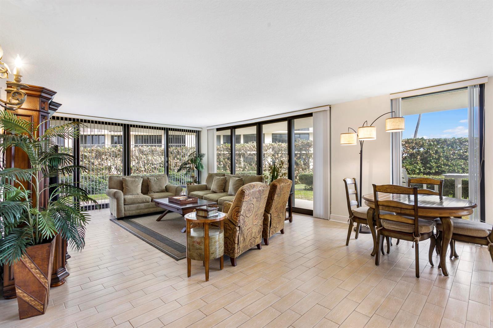 A living and dining area with tile floors, large windows, and neutral furniture — 3400 S Ocean Boulevard, Palm Beach FL 33480, PALM BEACH, FL