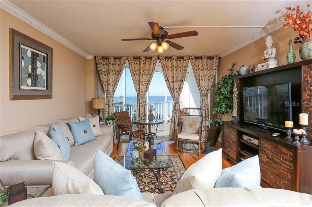 A living room with a beige sofa, glass coffee table, and balcony overlooking the ocean — 1770 BENJAMIN FRANKLIN DRIVE UNIT 603, SARASOTA, FL