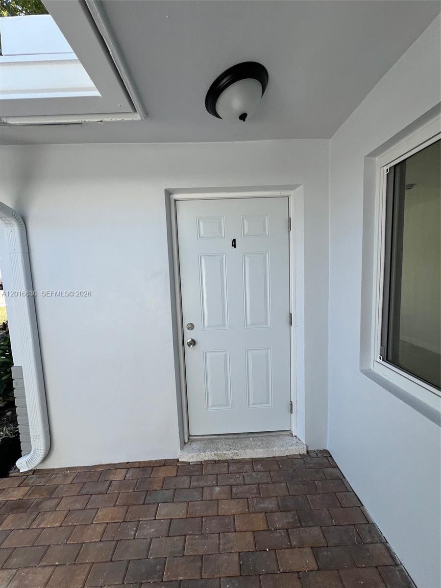 A white front door labeled with the number four sits on a brick patio — FORT LAUDERDALE, FL