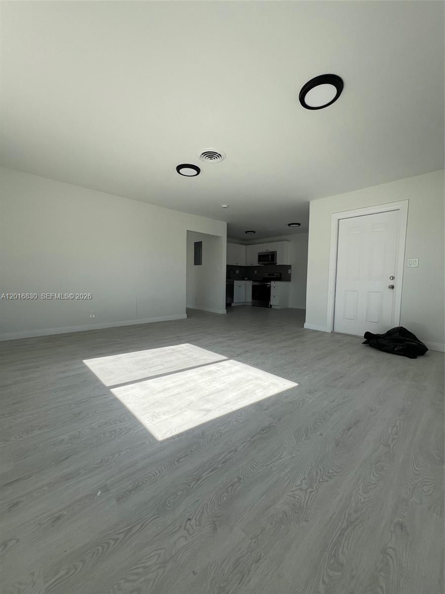 This open-concept living area features light wood-look flooring, white walls, and recessed ceiling lighting — FORT LAUDERDALE, FL
