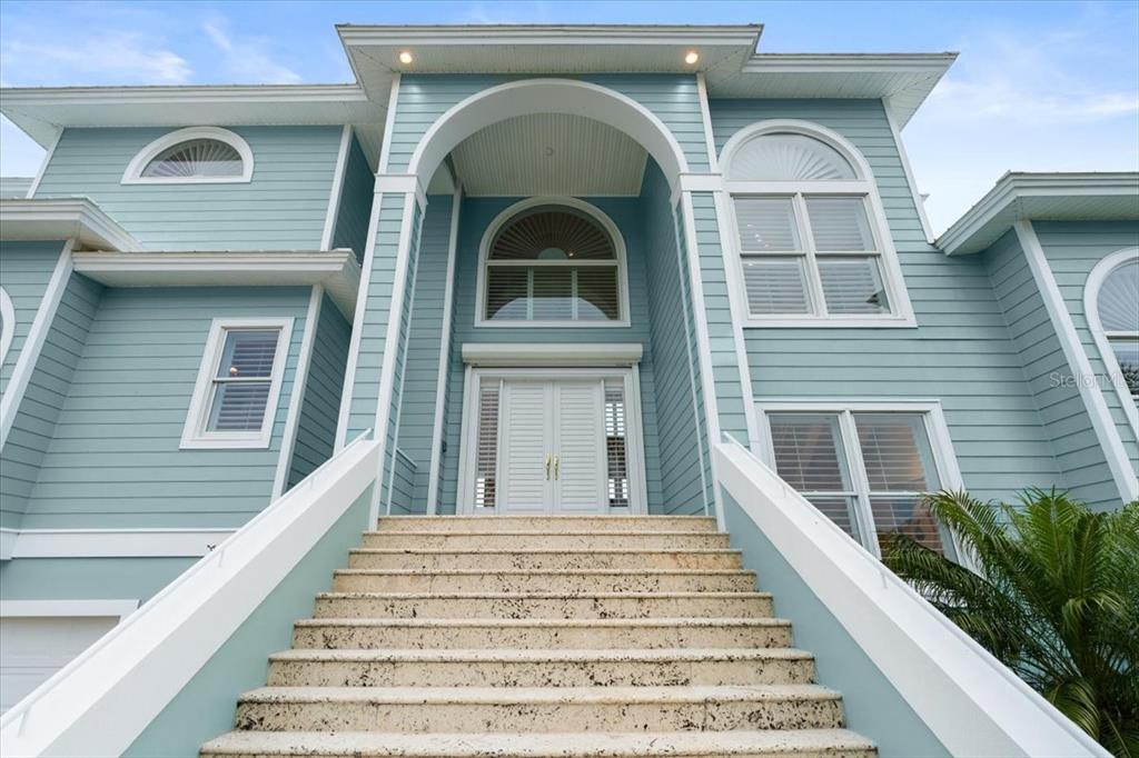 A light blue house features a grand staircase leading to a white double-door entrance — 2806 BAY VISTA COURT, NEW SMYRNA BEACH, FL