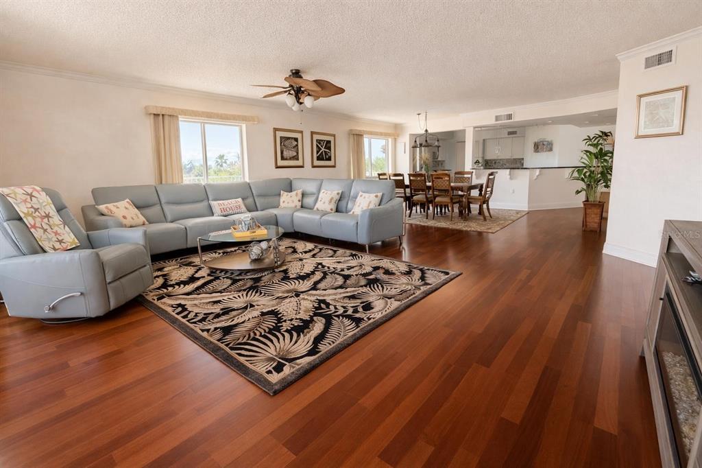 A living room with hardwood floors, a large sectional sofa, and an adjacent dining area — 420 HARDING AVENUE UNIT 301, COCOA BEACH, FL