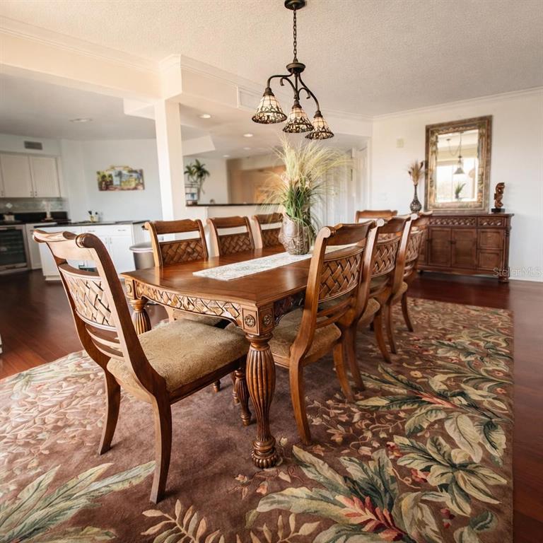 A dining room features a wooden table with six chairs, a floral rug, and pendant lighting — 420 HARDING AVENUE UNIT 301, COCOA BEACH, FL