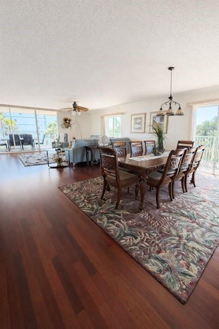 A dining area and living room with hardwood floors, a large area rug, and balcony access — 420 HARDING AVENUE UNIT 301, COCOA BEACH, FL