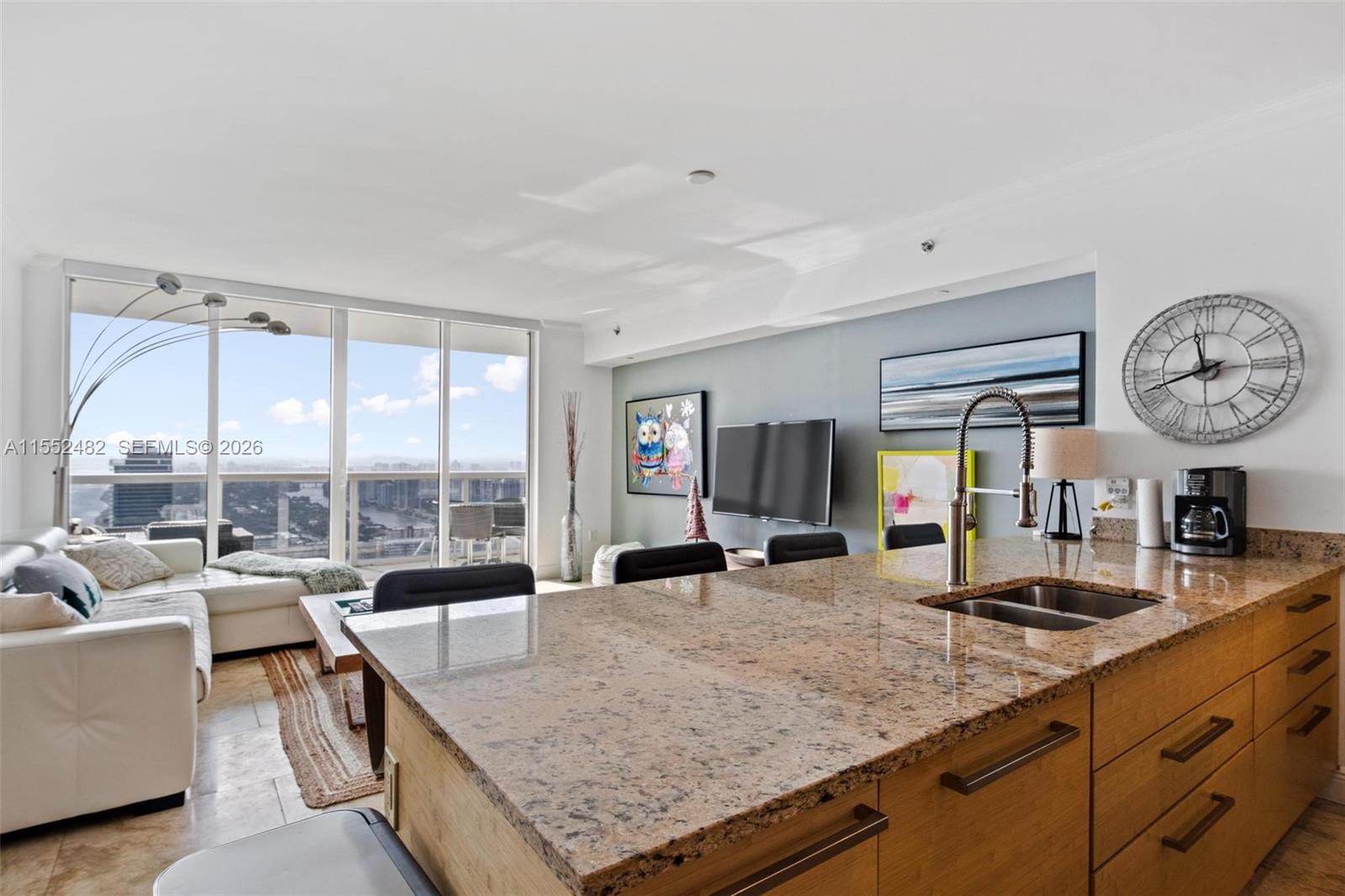 A kitchen island with granite countertops overlooks a living area with floor-to-ceiling windows — 1830 S Ocean Dr # 5005, Hallandale Beach FL 33009, HALLANDALE BEACH, FL