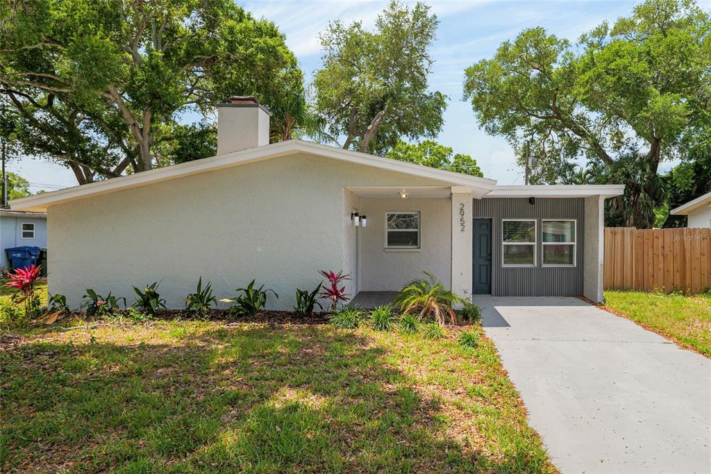 A single-story house with a light-colored stucco exterior, a chimney, and a concrete driveway — 2952 WEBLEY DRIVE, LARGO, FL