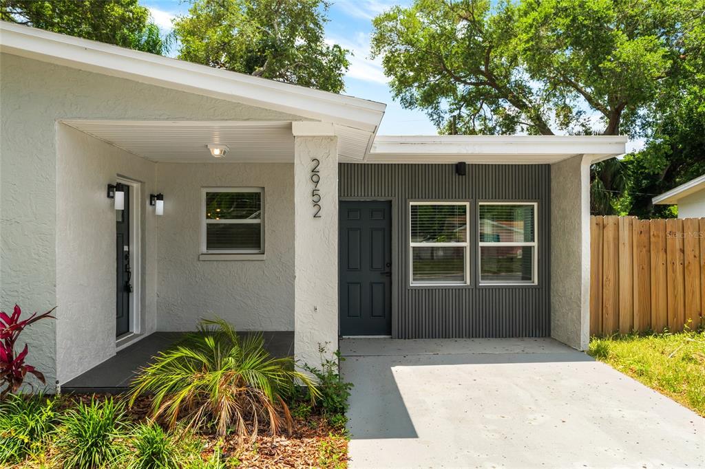 The exterior of a house features a covered porch, a dark door, and gray siding — 2952 WEBLEY DRIVE, LARGO, FL