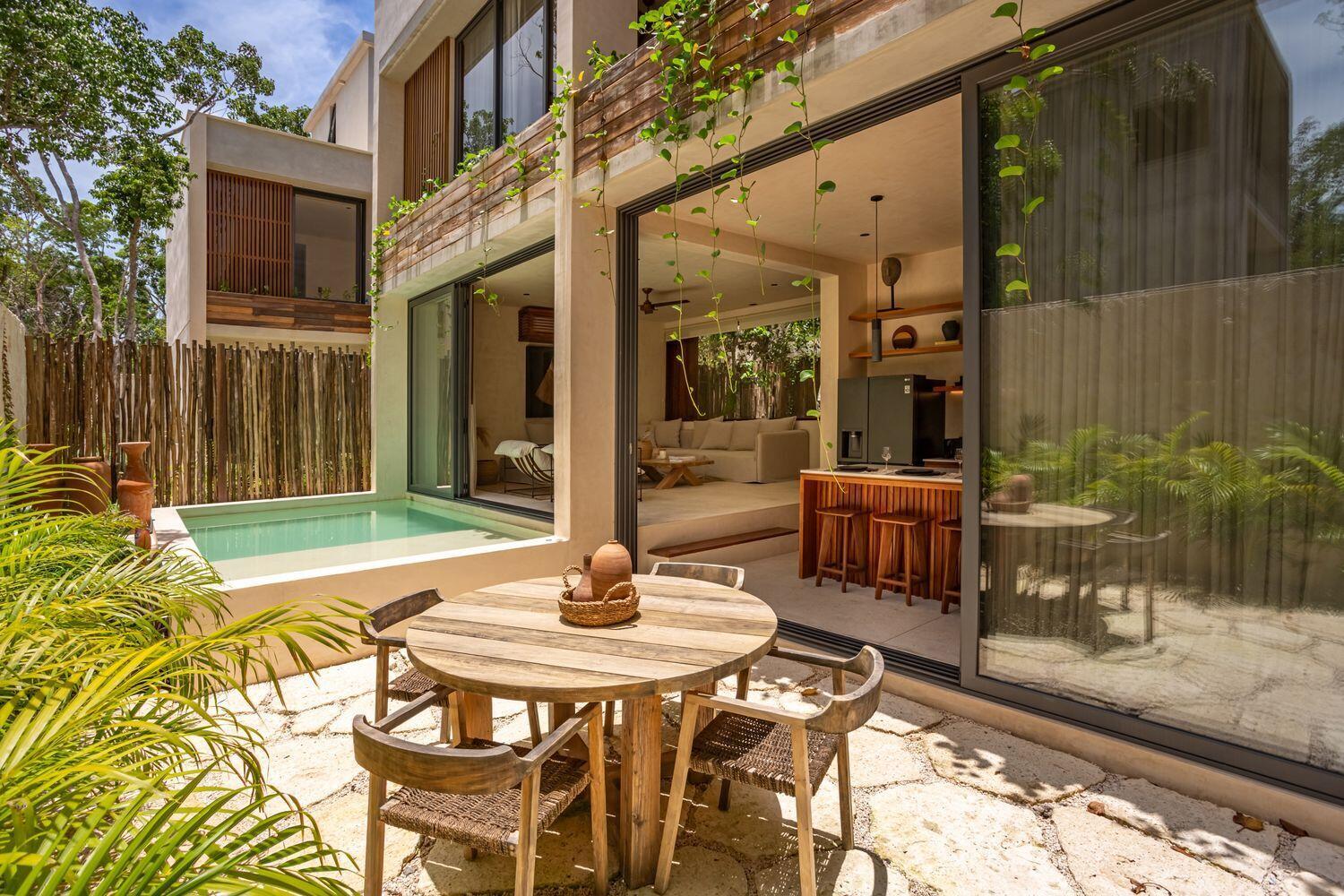 A patio with a round wooden table and chairs overlooks a small pool and villa — Amari Tulum 10 Avenida Norte & Calle Palma, FL