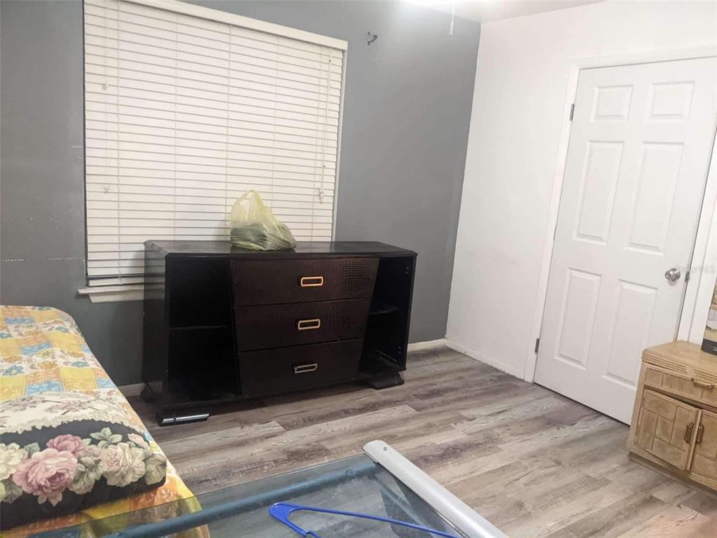 A bedroom features gray walls, wood-look flooring, a dark dresser, and a white door — 4000 SW 23RD STREET UNIT 4-103, #4, GAINESVILLE, FL
