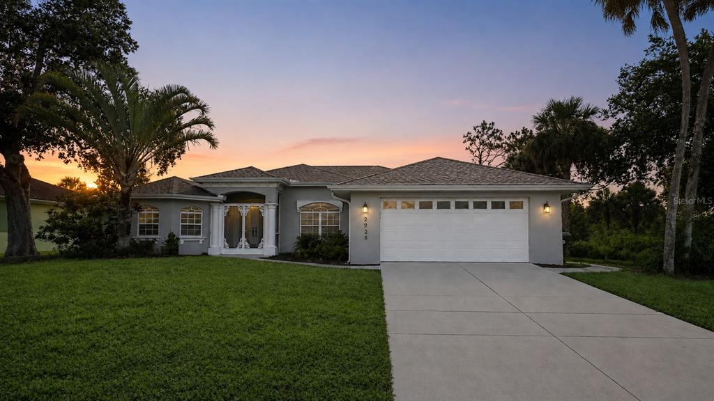 A single-story house with a white garage, gray exterior, and palm trees at sunset — 2928 ABBOTSFORD STREET, NORTH PORT, FL