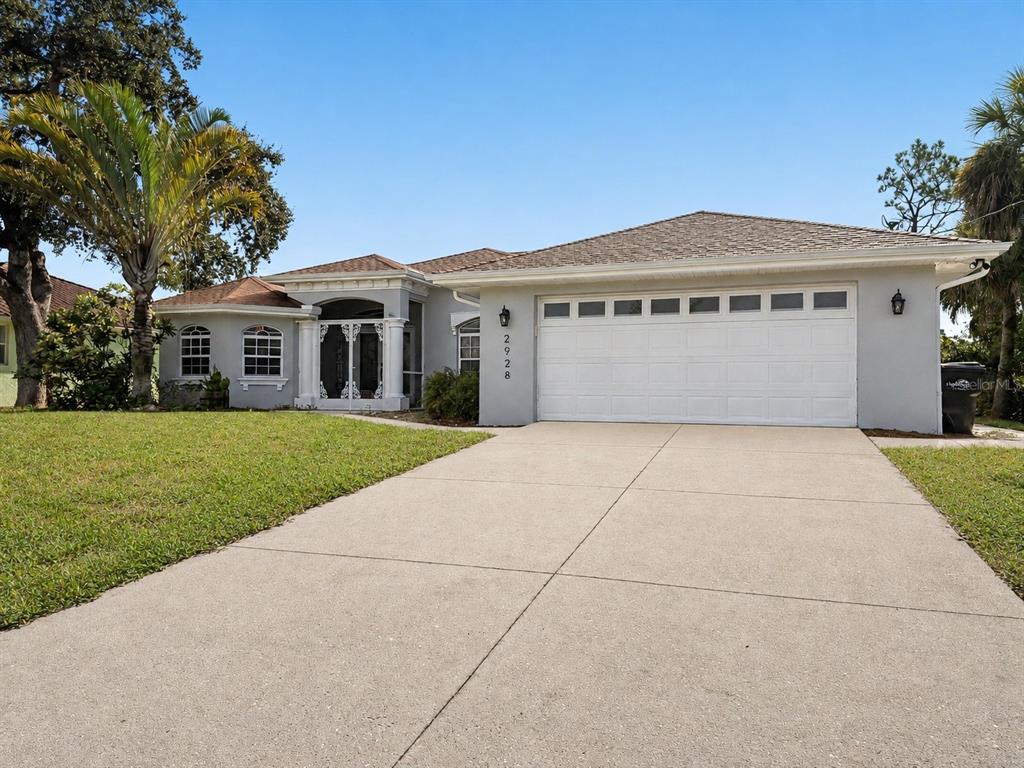 A single-story house with a light gray exterior, a two-car garage, and a concrete driveway — 2928 ABBOTSFORD STREET, NORTH PORT, FL