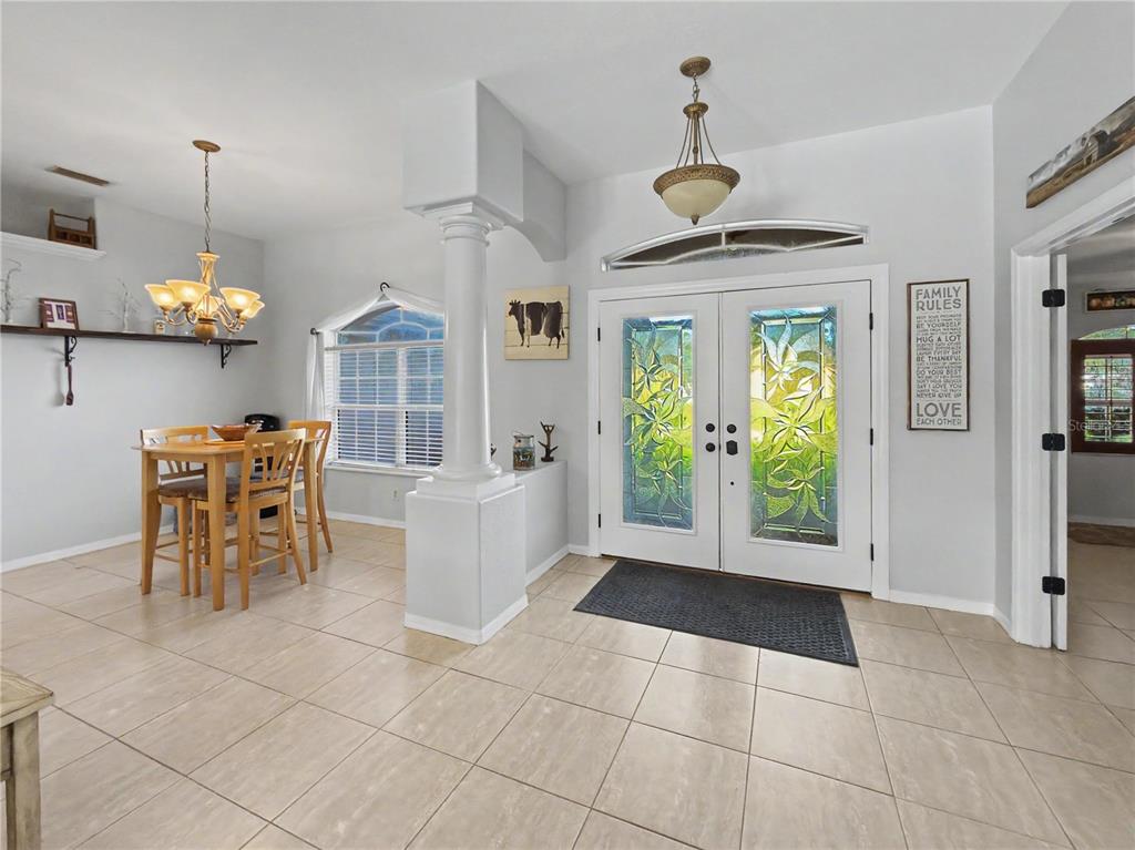 A bright dining area and entryway feature tile floors, a decorative column, and double glass doors — 2928 ABBOTSFORD STREET, NORTH PORT, FL