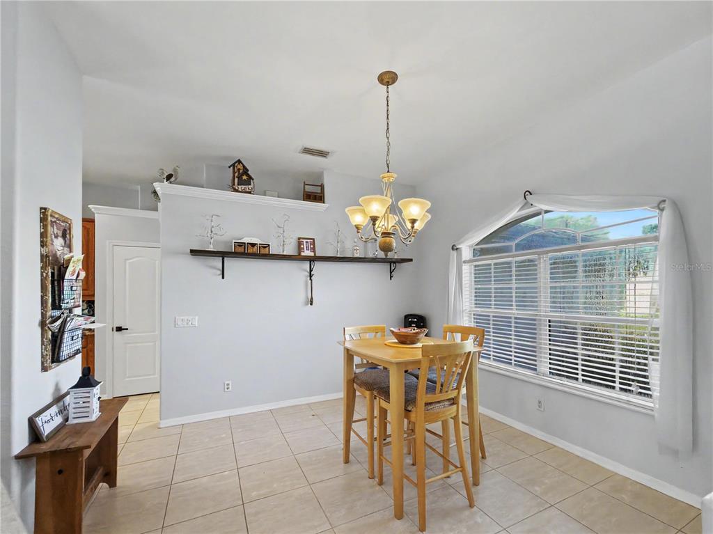 A dining area features a wooden table with four chairs, a chandelier, and a wall shelf — 2928 ABBOTSFORD STREET, NORTH PORT, FL