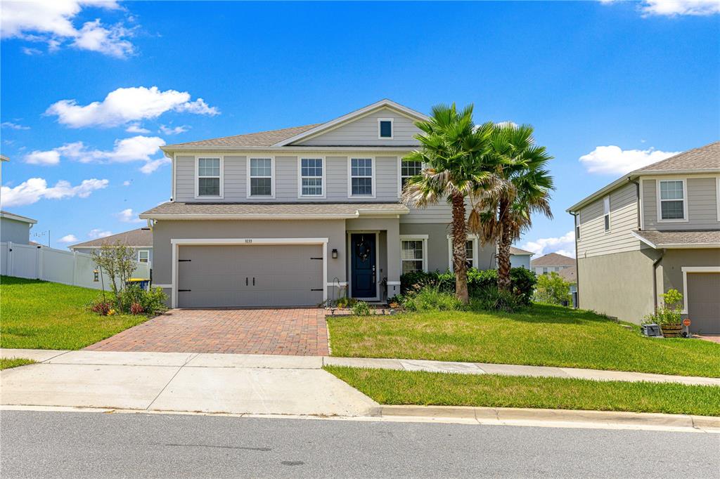 A two-story suburban house with a gray exterior, a two-car garage, and palm trees — 3133 HILL POINT STREET, MINNEOLA, FL
