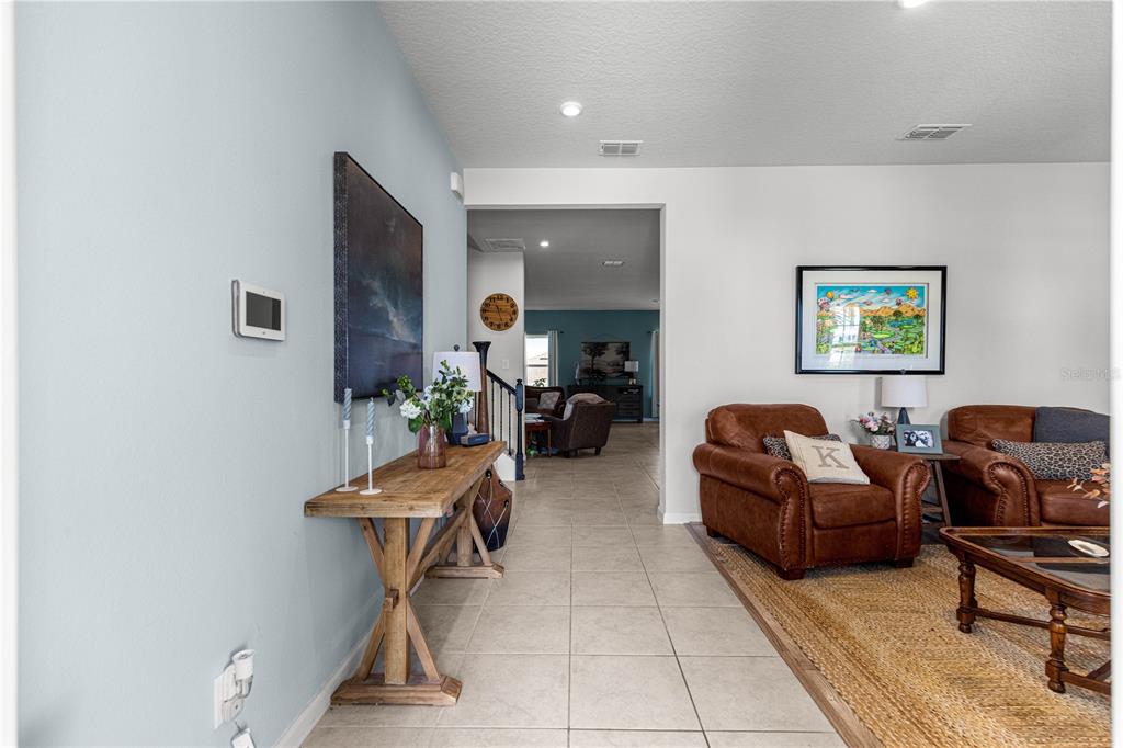 A living room with tile flooring, a wooden console table, and leather armchairs — 3133 HILL POINT STREET, MINNEOLA, FL