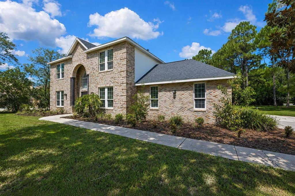 A two-story brick house with a dark shingled roof and a concrete walkway — 7377 ROYAL OAK DRIVE, WEEKI WACHEE, FL