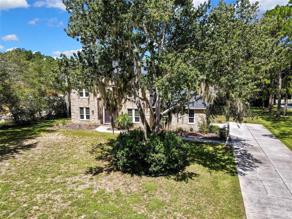 A two-story brick house with a large tree in the front yard and a driveway — 7377 ROYAL OAK DRIVE, WEEKI WACHEE, FL