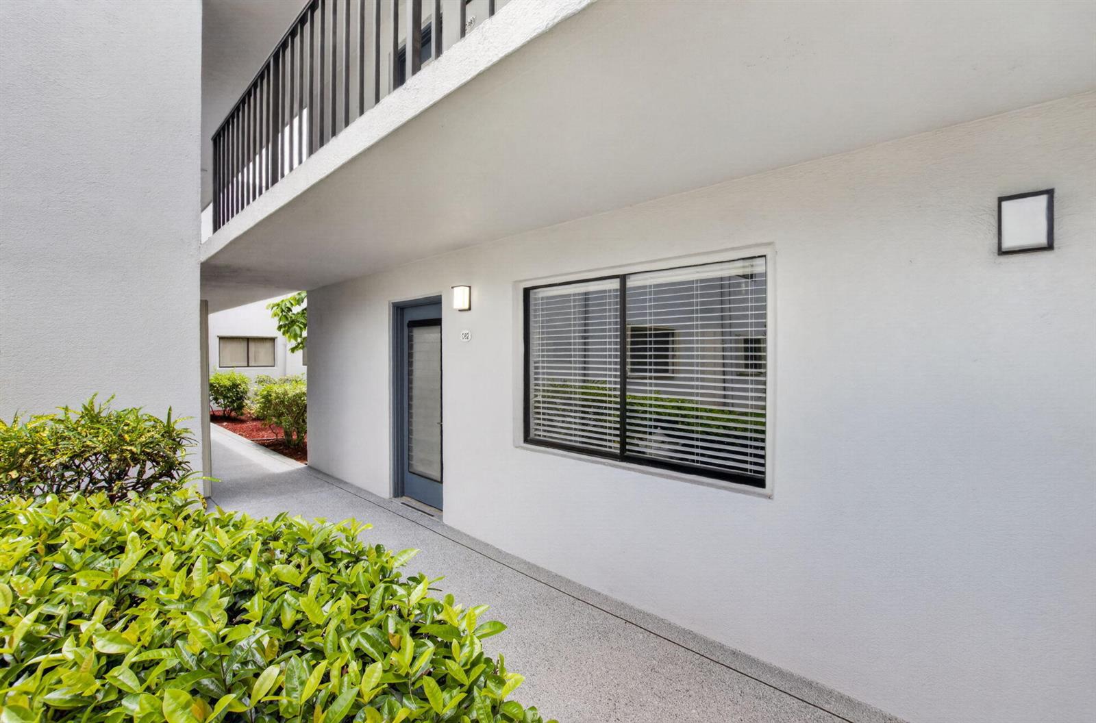 An exterior view of a ground-level apartment entrance with a window and walkway — 15054 Ashland Way # 82, Delray Beach FL 33484, DELRAY BEACH, FL