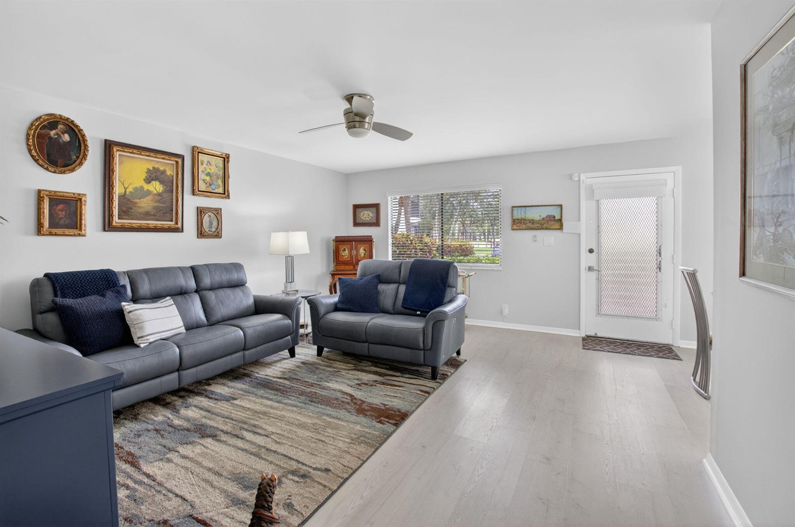 A living room features grey leather sofas, a patterned area rug, and a front door — 15054 Ashland Way # 82, Delray Beach FL 33484, DELRAY BEACH, FL