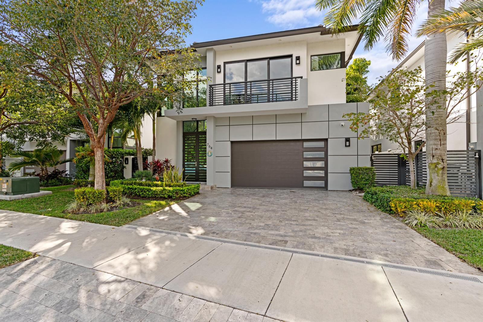 A modern two-story house features a gray paneled garage, a balcony, and a paved driveway — 764 Lake Trail, Delray Beach FL 33483, DELRAY BEACH, FL