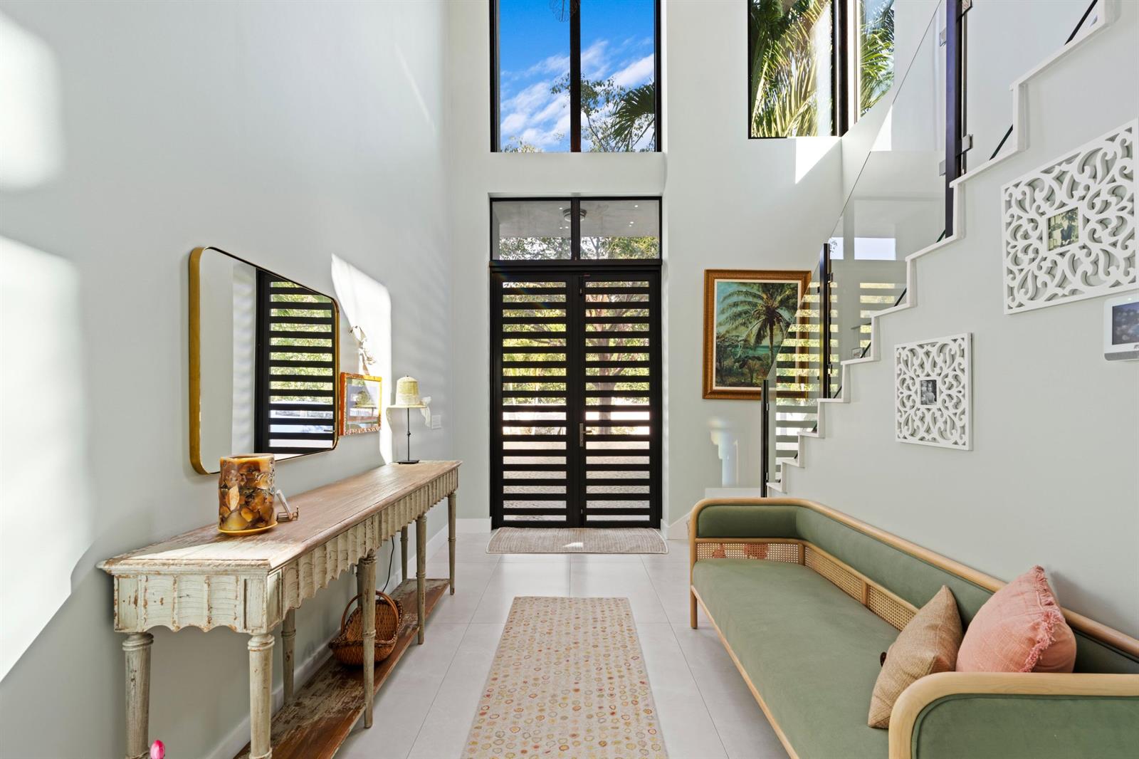 A bright entryway features a double-height ceiling, a slatted front door, and a staircase — 764 Lake Trail, Delray Beach FL 33483, DELRAY BEACH, FL