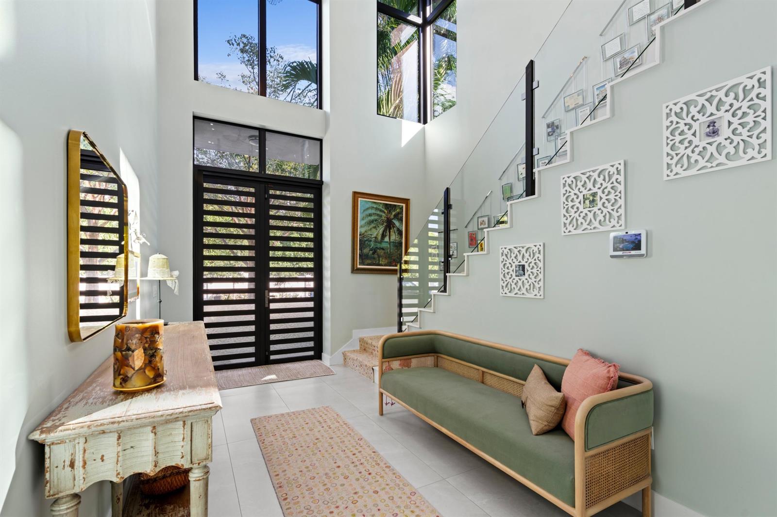 A bright entryway features a high ceiling, a modern staircase, and a green upholstered bench — 764 Lake Trail, Delray Beach FL 33483, DELRAY BEACH, FL