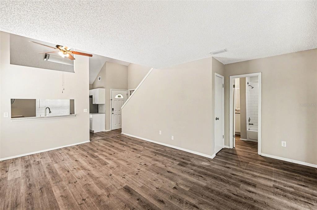 A living room with wood-look flooring, a ceiling fan, and an open doorway to a bathroom — 3408 LAUREL DALE DRIVE, TAMPA, FL