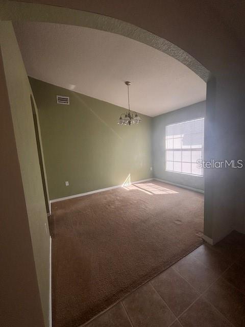 An empty room with tan carpet, sage green walls, and a hanging light fixture — 1716 MINNOW COURT, POINCIANA, FL