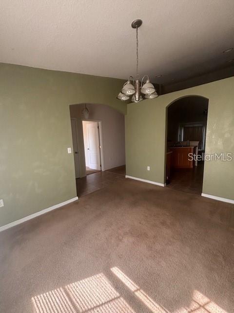 A carpeted dining area features a hanging chandelier and arched doorways leading to other rooms — 1716 MINNOW COURT, POINCIANA, FL