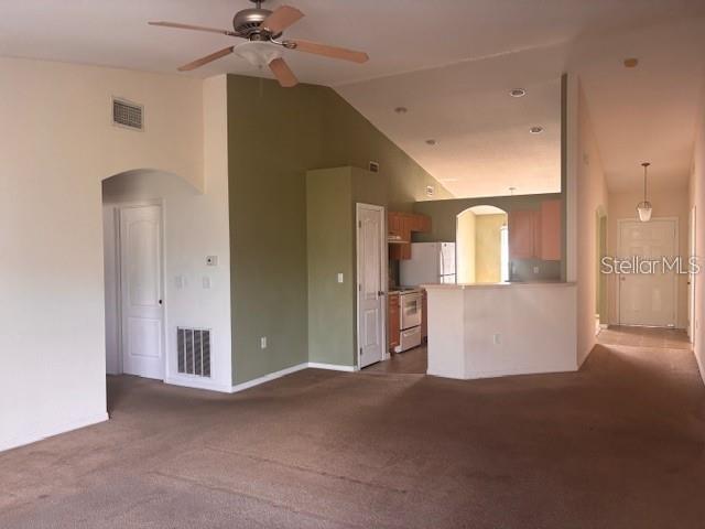 A living room with beige carpet leads to an open kitchen with a breakfast bar — 1716 MINNOW COURT, POINCIANA, FL