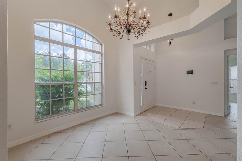 An entryway with tiled floors, a large arched window, and a decorative chandelier — 14339 VIBURNUM LN, ORLANDO, FL