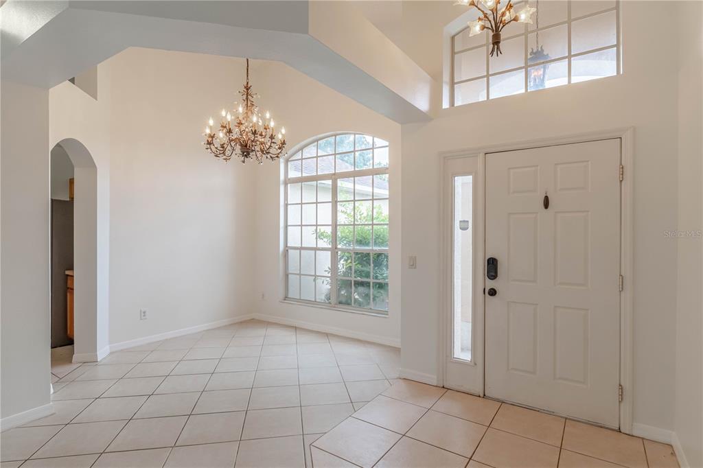 An entryway with tile flooring, a chandelier, a high ceiling, and a white front door — 14339 VIBURNUM LN, ORLANDO, FL