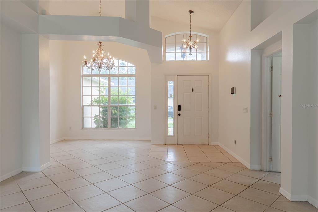 A bright foyer and dining area feature tiled floors, high ceilings, and two crystal chandeliers — 14339 VIBURNUM LN, ORLANDO, FL