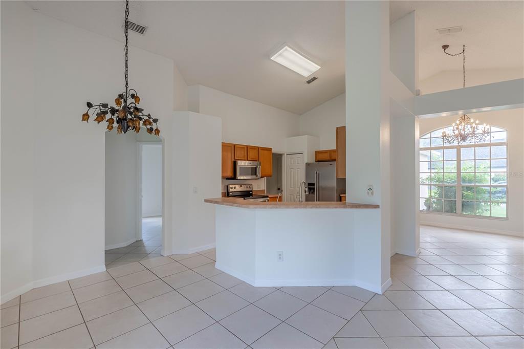 A kitchen with wood cabinets and a breakfast bar overlooks a tiled dining area — 14339 VIBURNUM LN, ORLANDO, FL