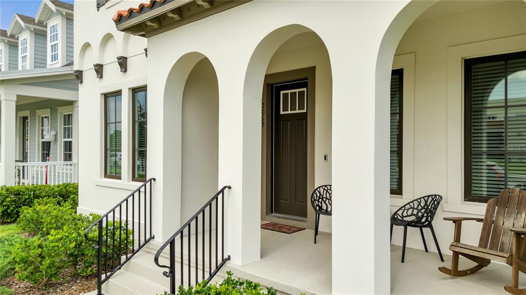 A white stucco house exterior features an arched covered porch with a dark front door — 2069 CELEBRATION BOULEVARD, KISSIMMEE, FL
