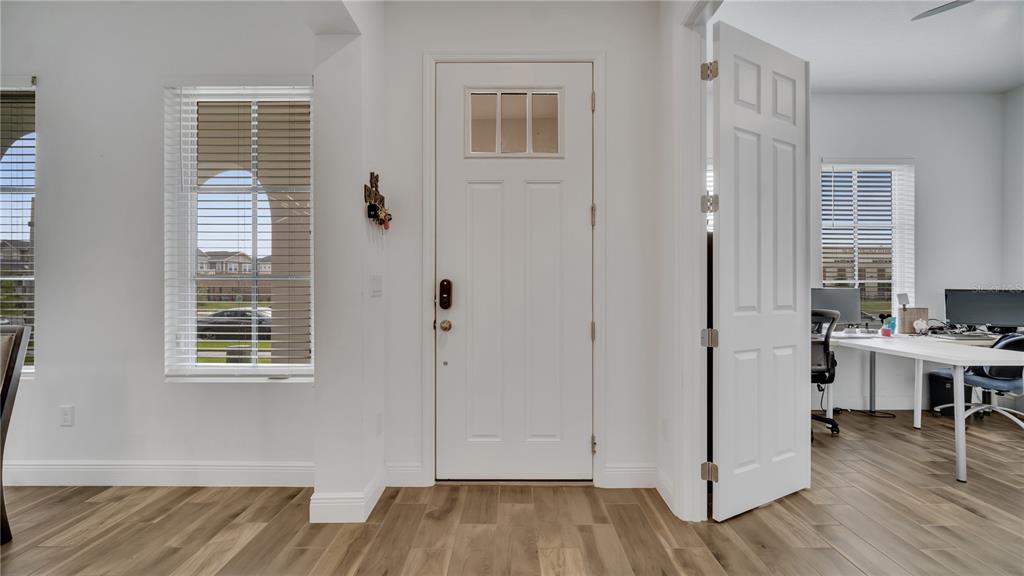 An interior view shows a white front door, wood-look flooring, and an adjacent home office — 2069 CELEBRATION BOULEVARD, KISSIMMEE, FL