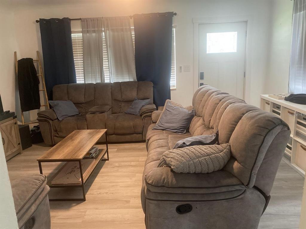 A living room features two brown reclining sofas, a wood coffee table, and light flooring — 1110 E EDGEWOOD DRIVE, LAKELAND, FL