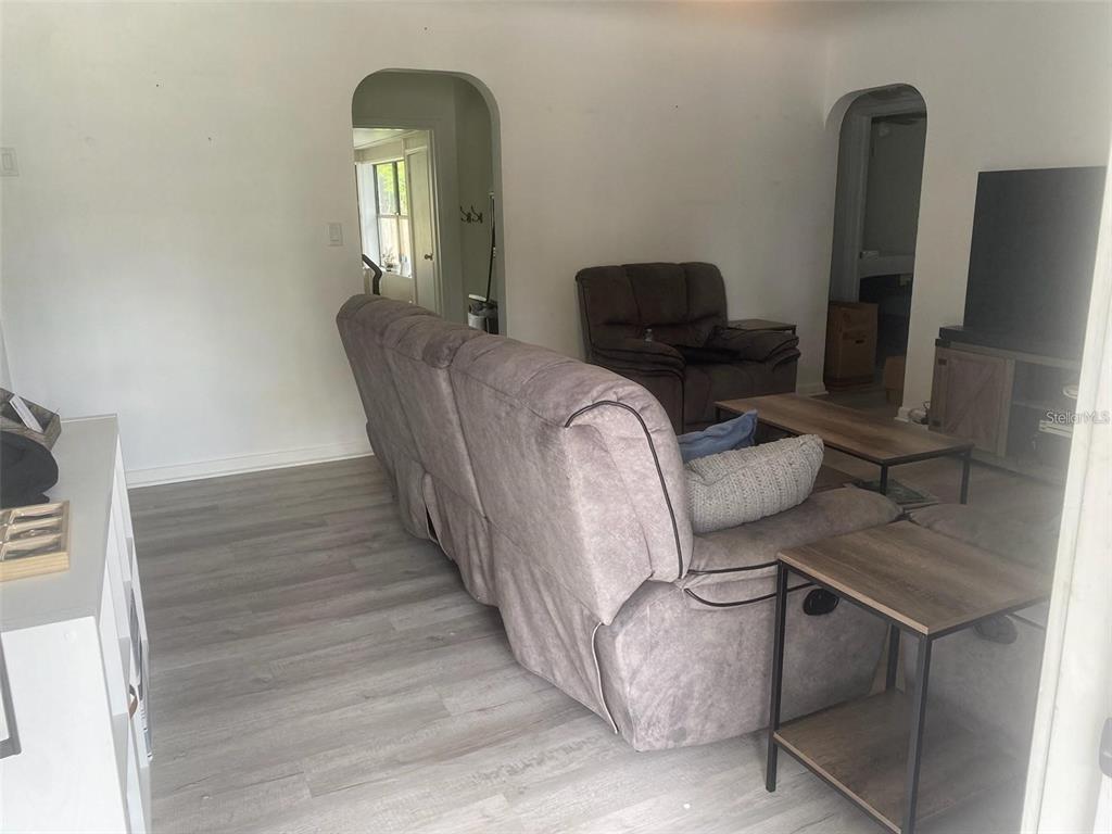 A living room features gray wood-look flooring, a gray sofa, and two arched doorways — 1110 E EDGEWOOD DRIVE, LAKELAND, FL