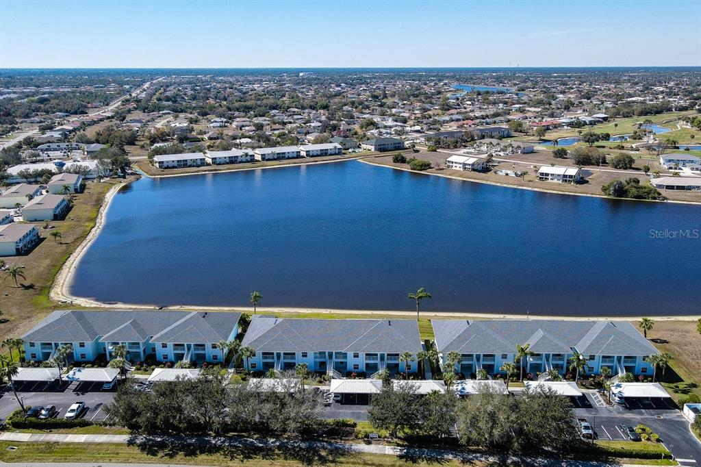 An aerial view shows a large lake surrounded by residential apartment buildings and parking lots — 1479 SAN CRISTOBAL AVENUE UNIT 2104, PUNTA GORDA, FL