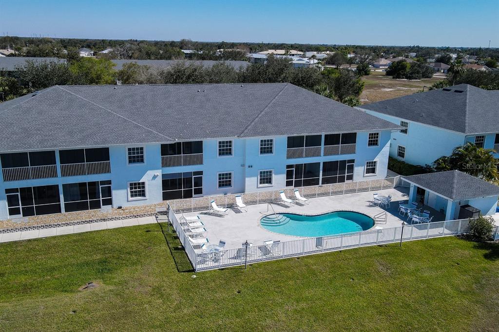 An aerial view of a two-story apartment building with a fenced pool and patio — 1479 SAN CRISTOBAL AVENUE UNIT 2104, PUNTA GORDA, FL