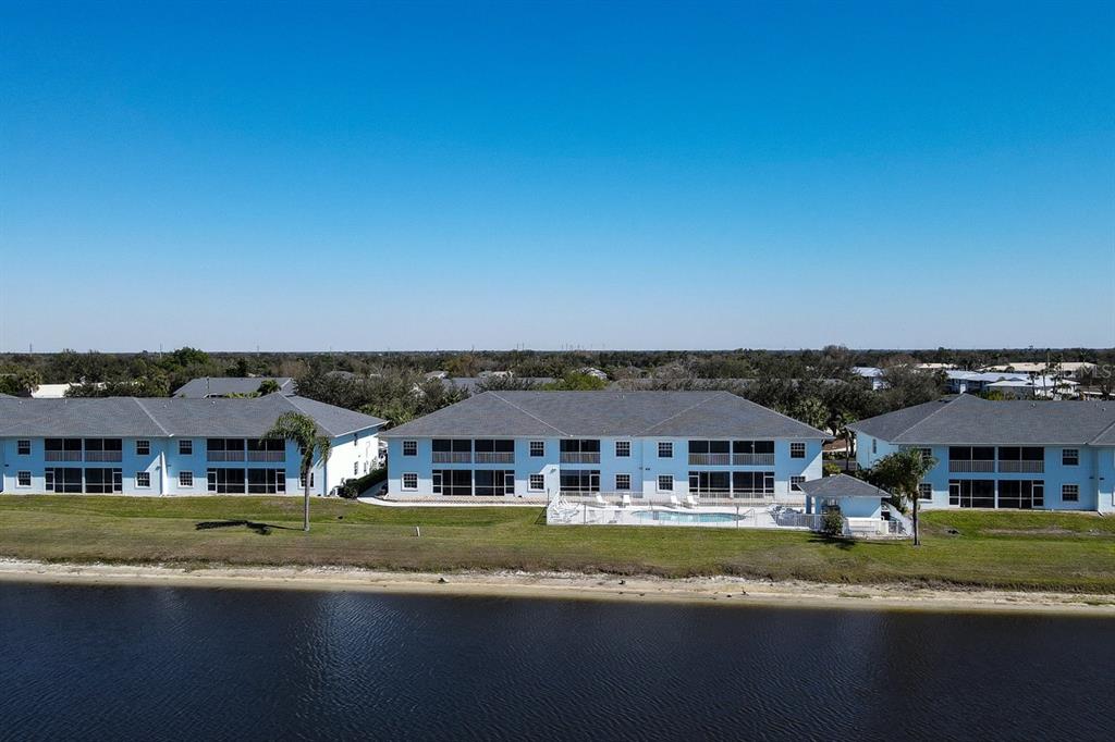 An aerial view shows three multi-story apartment buildings situated along a waterfront with a pool — 1479 SAN CRISTOBAL AVENUE UNIT 2104, PUNTA GORDA, FL