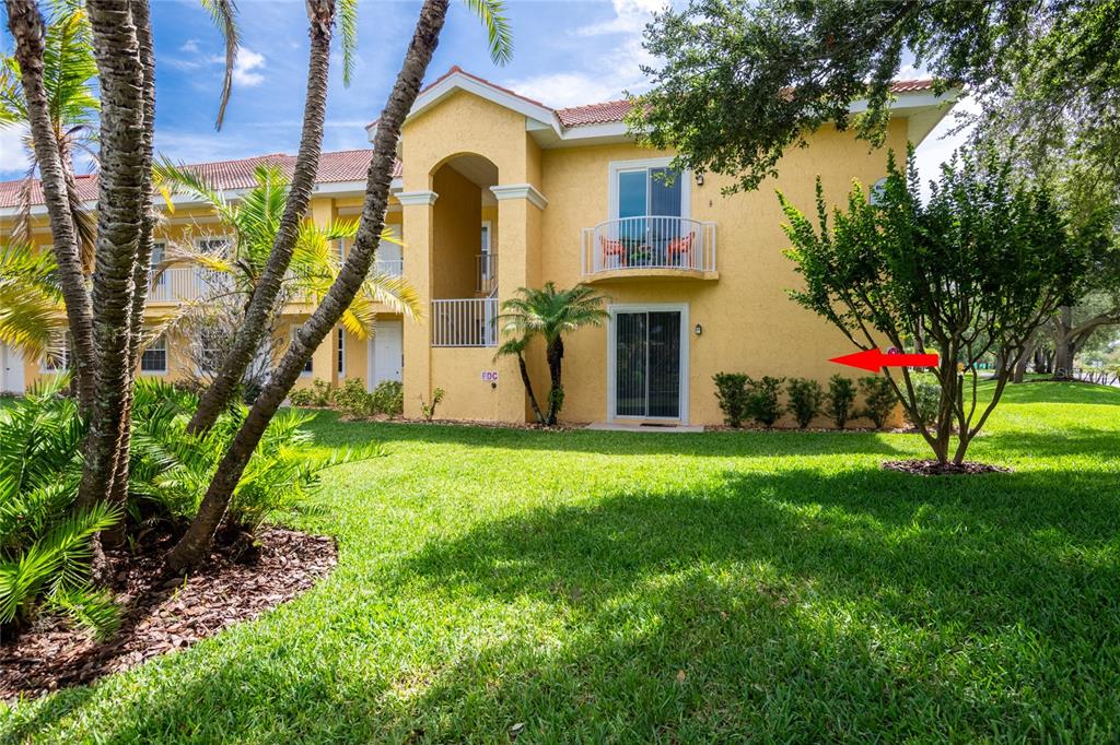 A two-story yellow stucco apartment building with balconies and a grassy lawn in front — 6714 DALI AVENUE UNIT 101, LAND O LAKES, FL