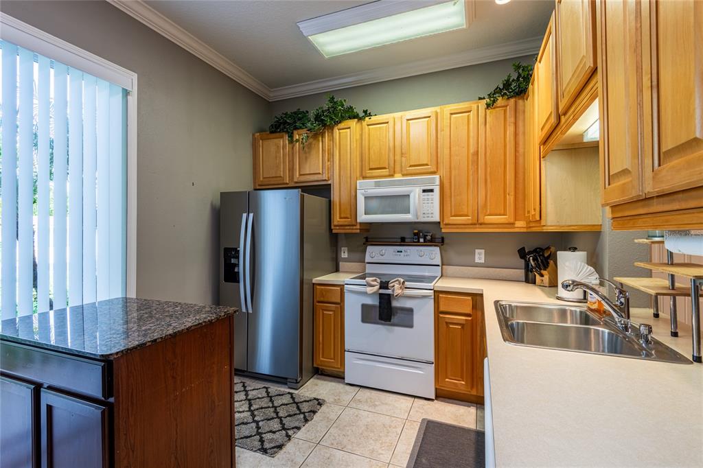 A kitchen with light wood cabinets, stainless steel appliances, and a granite-topped island — 6714 DALI AVENUE UNIT 101, LAND O LAKES, FL