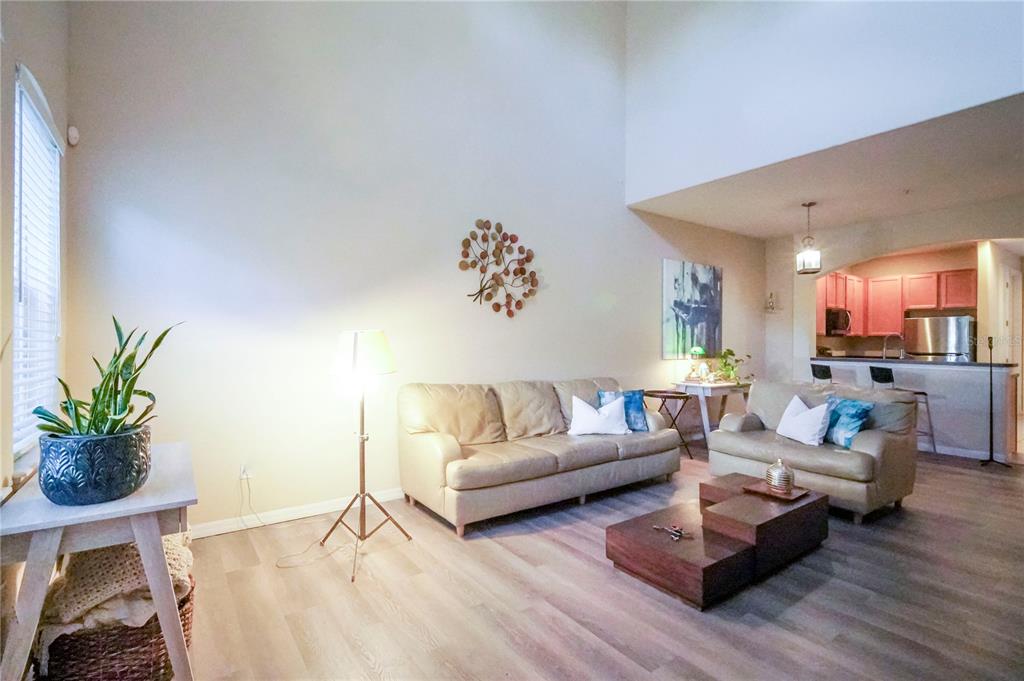 A living room with light wood floors, two beige sofas, and a high vaulted ceiling — 2925 AQUA VIRGO LOOP UNIT 25, ORLANDO, FL