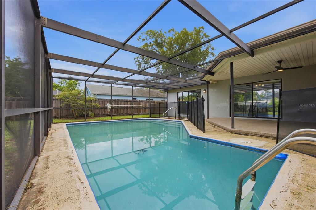 A screened-in swimming pool with a concrete deck and a covered patio area — 8373 CAMPHOR DRIVE, SPRING HILL, FL