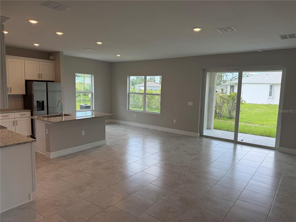 An open-concept kitchen and living area features tile flooring, granite countertops, and sliding glass doors — 2307 ZUYDER TERRACE, NORTH PORT, FL