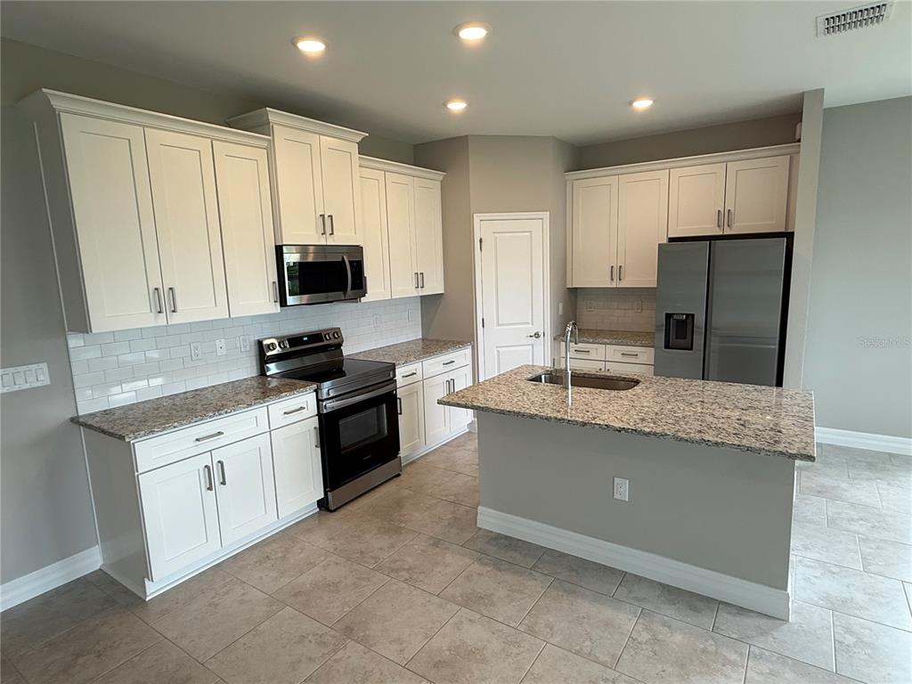 A kitchen features white cabinets, granite countertops, stainless steel appliances, and a central island — 2307 ZUYDER TERRACE, NORTH PORT, FL