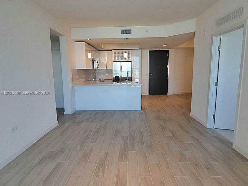 An open-concept kitchen with white cabinetry and a breakfast bar overlooks a living area — 999 SW 1 AVE # 1907, Miami FL 33130, MIAMI, FL