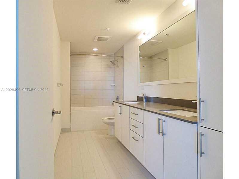 A modern bathroom features a white vanity, a large mirror, and a tiled tub-shower combination — 999 SW 1 AVE # 1907, Miami FL 33130, MIAMI, FL